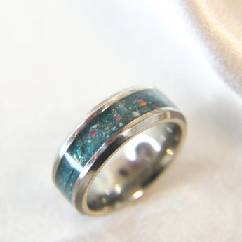 Titanium band, forest green shimmer, pink crushed opal, subtle opalescent flecks, fur, lightly sprinkled ashes and sand