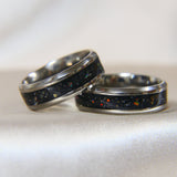Titanium band, black shimmer, lightly sprinkled ashes, aquamarine opal ( reflects as red on black shimmer base)