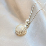 A sterling silver crown breastmilk pendant with breastmilk and white opal