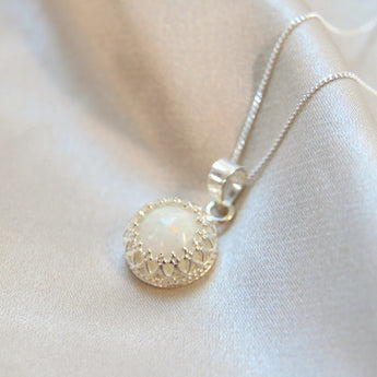 A sterling silver crown breastmilk pendant with breastmilk and white opal