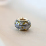 Silver bead, charcoal grey shimmer, breastmilk, hair and umbilical cord, subtle silver flecks