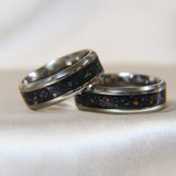 Titanium band, black shimmer, lightly sprinkled ashes, aquamarine opal ( reflects as red on black shimmer base)